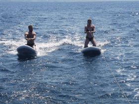 A couple enjoys paddleboarding on the open water, showcasing a fun and adventurous day on the sea.
