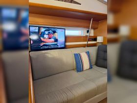 Cozy interior seating area of a boat featuring a comfortable couch and a television, perfect for relaxing during trips on the water.