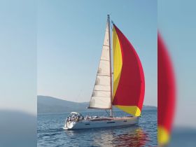 A vibrant sailboat with a colorful spinnaker glides through the water, showcasing a perfect day for sailing with friends.