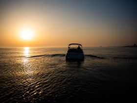 A serene sunset view of a boat cruising on calm waters, creating a picturesque scene perfect for evening outings.