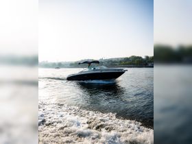 A speedboat glides through the water with a person at the helm, showcasing a perfect day for boating on the river.