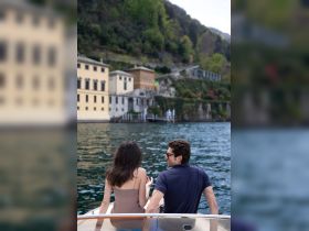 A couple enjoys a scenic boat ride, taking in the beautiful waterfront views — perfect for romantic getaways or leisurely excursions.