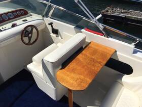 A well-appointed helm area featuring a steering wheel, seating, and a wooden table, perfect for navigating the waters in comfort.