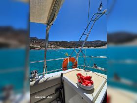 A refreshing plate of watermelon sits on the deck of a sailboat, perfect for enjoying a snack while cruising in clear turquoise waters.