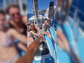 A joyful group toasts with cocktails aboard a sailboat, capturing the essence of celebration and camaraderie on the open water.
