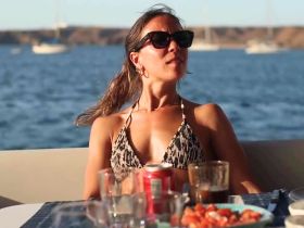 A woman enjoys a relaxing moment on a boat, sipping drinks and soaking in the beautiful sunset views — perfect for a serene day on the water.