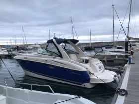 A sleek Monterey yacht docked at the marina, showcasing its elegant design and vibrant blue color against a cloudy sky.