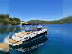 A sleek speedboat docked in calm waters, surrounded by lush greenery and hills — perfect for a day of exploration on the water.