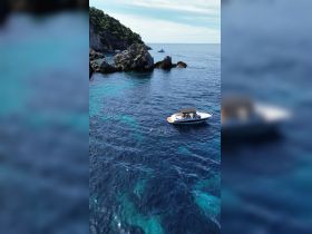 A group enjoys a refreshing swim in the clear waters near a boat, surrounded by stunning rocky scenery — a perfect day for adventure on the water.