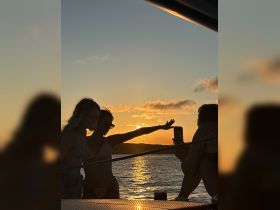A group of friends captures a beautiful sunset while enjoying their time on a boat, creating unforgettable memories against a stunning backdrop.