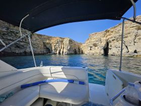 A view from inside a boat showcasing the comfortable seating area with stunning rocky cliffs in the background, perfect for relaxing while enjoying the scenery.