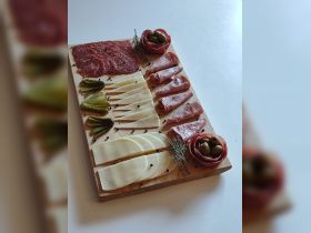 A beautifully arranged charcuterie board featuring an assortment of meats, cheeses, and pickles, perfect for onboard snacking during a boat trip.