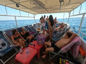 A lively group enjoys a relaxing day on a boat, lounging and socializing with drinks in hand — perfect for summer parties and fun on the water.