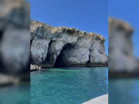 A stunning view of a rocky coastline with turquoise waters, perfect for capturing the beauty of nature during a boating adventure.