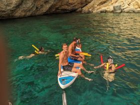 A group enjoys a fun day of snorkeling and paddleboarding in crystal-clear waters, showcasing the perfect summer adventure.