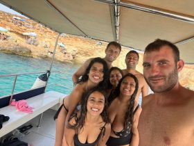 A cheerful group of friends enjoys a fun day on the boat, capturing memories against a stunning coastal backdrop — perfect for summer adventures.