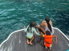 A joyful family enjoys time on the boat, with children preparing to jump into the clear blue waters — a perfect moment for summer fun and adventure.