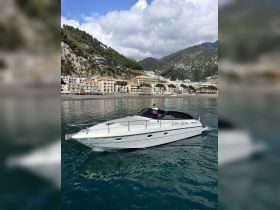 A sleek speedboat navigates the tranquil waters, showcasing its elegant design against a picturesque coastal backdrop.