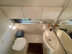 A clean and well-equipped bathroom inside a boat, featuring a toilet, sink, and storage, ideal for comfortable cruising.