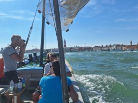 A group enjoys a scenic boat ride in Venice, capturing memories with photography against a stunning city backdrop — perfect for exploring the iconic canals.