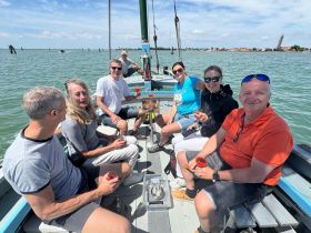 A cheerful group enjoys cocktails aboard a sailboat, capturing the essence of a fun day on the water with friends.