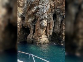 A stunning view of rocky cliffs rising above crystal-clear waters, showcasing the natural beauty of the coastline — perfect for scenic boat tours.