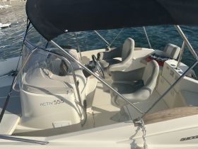 Interior view of the helm and seating area on an Activ 555 boat, showcasing the modern design and comfortable layout for a day on the water.