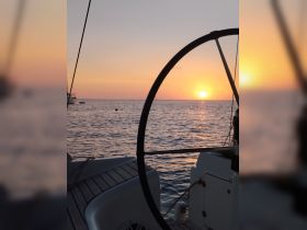 A serene sunset view from the helm of a sailboat, showcasing the tranquil waters and vibrant sky — perfect for peaceful evening cruises.