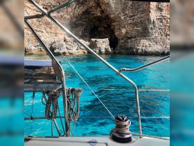 A stunning view from a boat showcasing crystal-clear turquoise waters and rocky cliffs, perfect for exploring coastal caves and enjoying the beauty of nature.