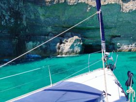 A stunning view of a sailboat navigating through crystal-clear turquoise waters, with dramatic cliffs in the background, perfect for exploring coastal landscapes.