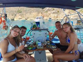 A cheerful group enjoys a meal and cocktails aboard a yacht, capturing the essence of a perfect day on the water with friends.