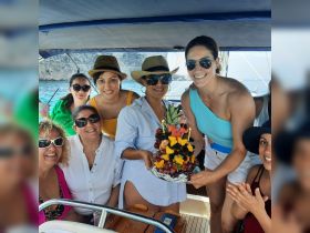 A joyful group of friends celebrates with a beautifully arranged fruit platter aboard a boat, perfect for memorable gatherings and special occasions on the water.