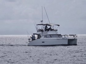 A fishing boat navigates the ocean with anglers on board, showcasing the thrill of deep-sea fishing adventures.