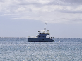 A serene view of a yacht cruising in calm waters, showcasing its sleek design against a picturesque backdrop.