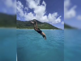 A person dives into the crystal-clear waters, capturing the thrill of adventure in a stunning island setting.