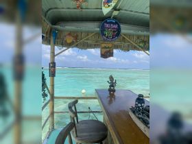 A vibrant tiki bar setup featuring colorful decorations and a stunning view of turquoise waters, perfect for enjoying tropical cocktails in a relaxing atmosphere.