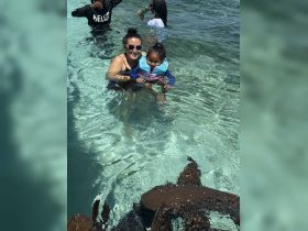 A joyful moment as a woman and a child interact with stingrays in crystal-clear waters, showcasing a unique wildlife experience perfect for family adventures.