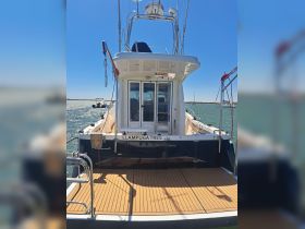 A clear view of the back of the 'LLAMPUGA TRES' boat, showcasing its sleek design and spacious deck, perfect for fishing or leisure activities on the water.