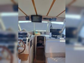 The interior helm of a boat featuring modern navigation equipment and comfortable seating, ideal for steering and managing onboard activities.