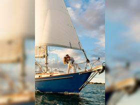 A romantic moment captured as a couple shares a kiss aboard a sailboat, perfect for celebrating love on the water.
