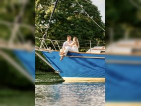 A couple shares a romantic moment on the bow of a boat, creating a perfect backdrop for love and celebration on the water.