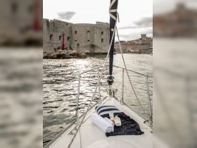 A relaxing setup on the bow of a boat featuring towels, sunscreen, and a pillow, perfect for a day of sunbathing and enjoying the water.