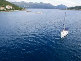 A stunning aerial view of a sailboat navigating through tranquil waters, surrounded by picturesque coastal scenery — perfect for sailing enthusiasts and nature lovers.