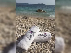 Two branded towels resting on a pebbly beach, perfect for a relaxing day by the water. Ideal for boat trips or beach outings in Dubrovnik.