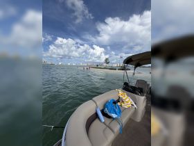 A scenic view from a pontoon boat at a sandbar, with people enjoying the beach in the background — perfect for a fun day on the water.