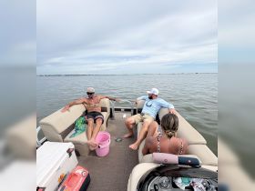 A group of friends relaxes on a pontoon boat, enjoying the serene waters — perfect for a day of fun and relaxation on the water.