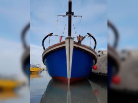 A striking view of a blue boat docked at the marina, showcasing its unique design and structure against a serene sky.