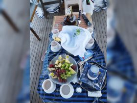 A beautifully arranged table featuring a delicious cake, fresh fruit, and cocktails, perfect for a celebratory gathering on board.