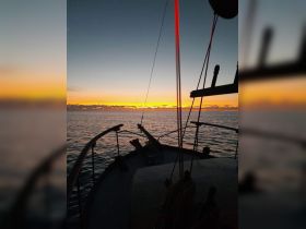 A serene sunset view from the deck of a boat, capturing the tranquil waters and vibrant sky — perfect for evening cruises.