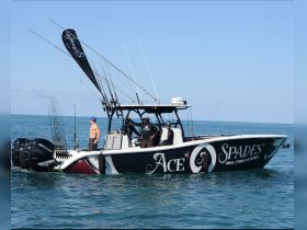A fishing boat named 'Ace of Spades' is seen on the ocean with a group of individuals preparing for a day of fishing, showcasing the excitement of marine adventures.